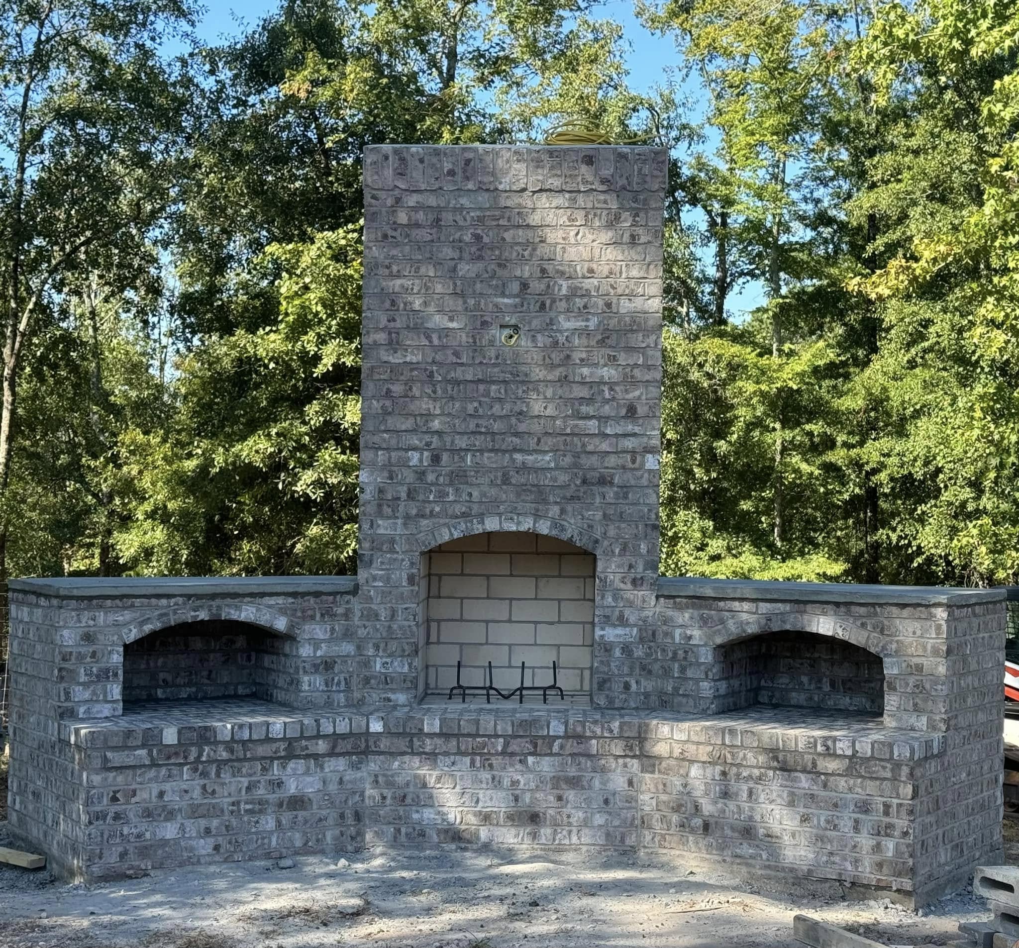 Outdoor brick fireplace with built-in seating by Verdin Masonry